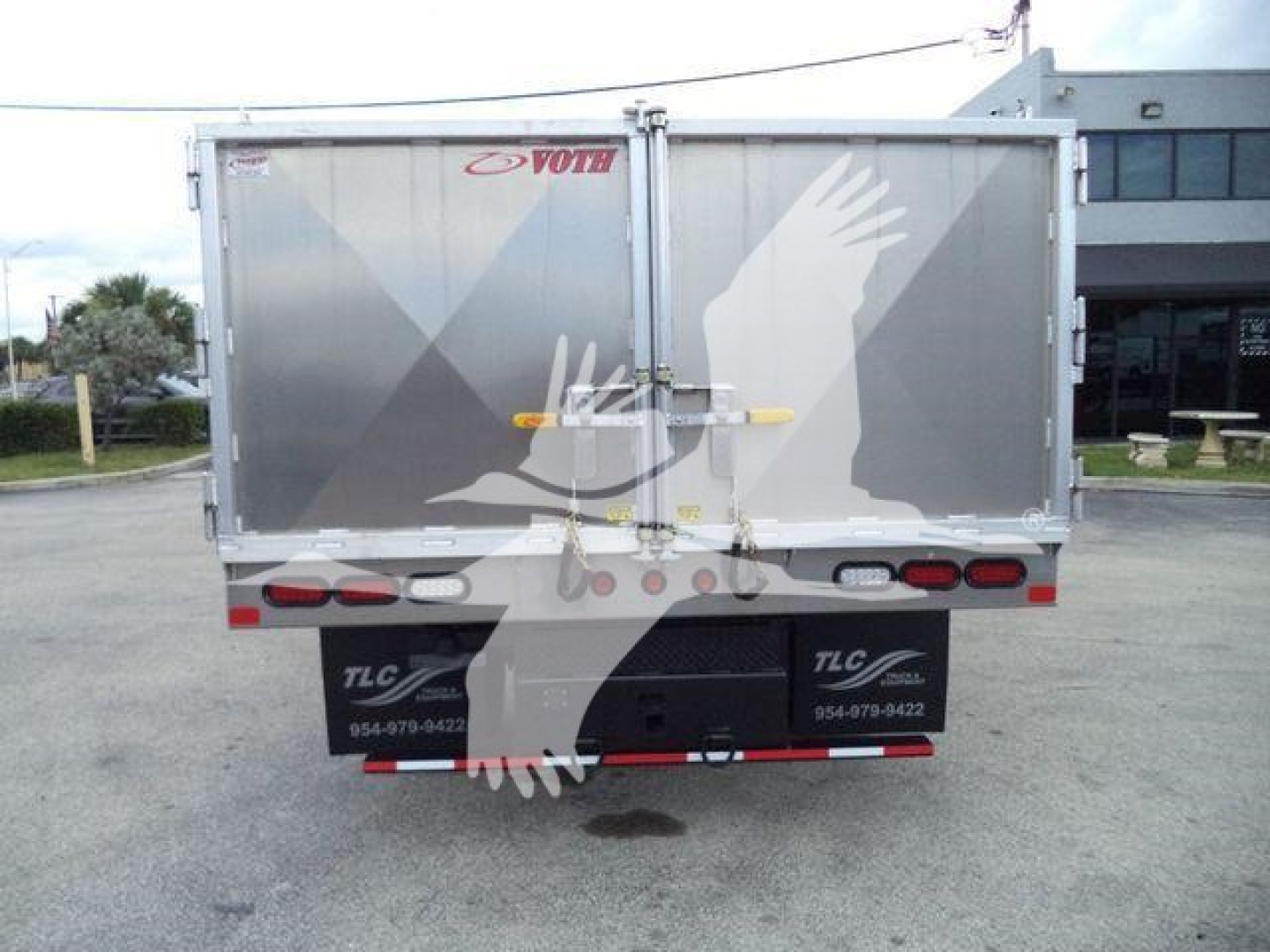 Rear view of a light gray GMC/Isuzu W4500 truck with a cargo trailer, showing TLC/white silhouette watermark, tail lights, and rear bumper.