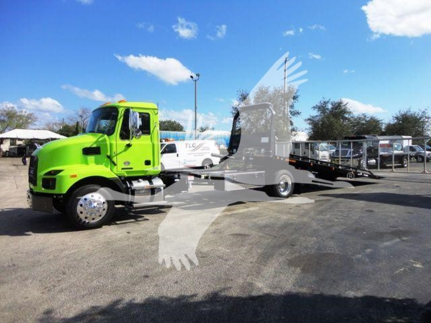 Green 2026 Mack MD6 rollback truck with flatbed, side view showing cab and wheel; faint watermark overlay of a winged logo.