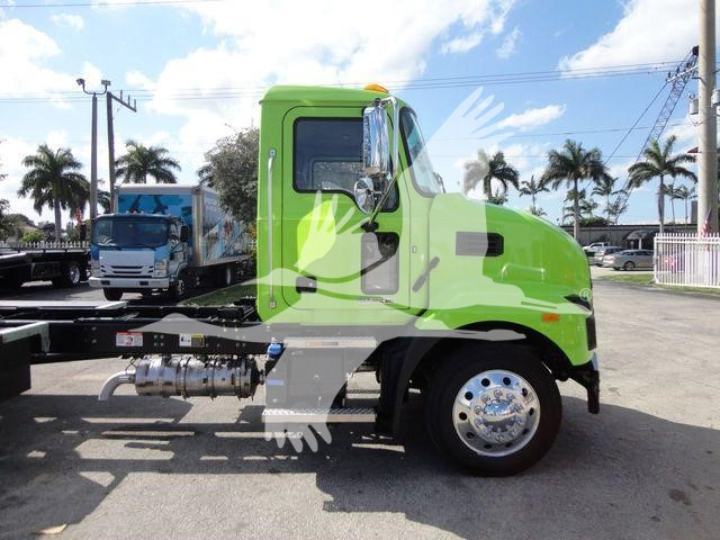 Green Mack MD6 truck cab in profile, side view showing front wheel, fuel tanks, and chassis; no visible equipment labels readable.