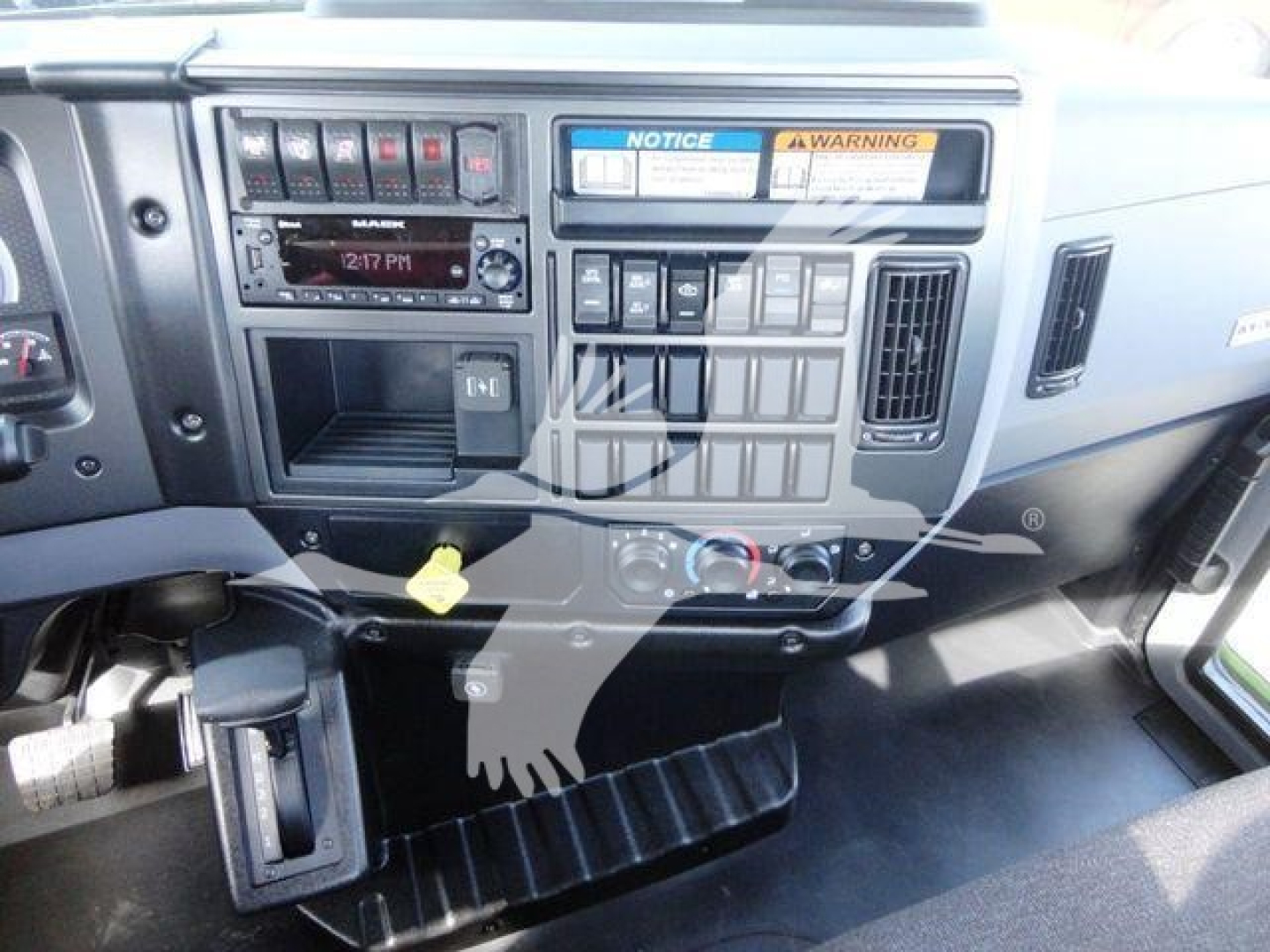 Dashboard of a Mack MD6 truck showing control panel and switches and a digital radio display.