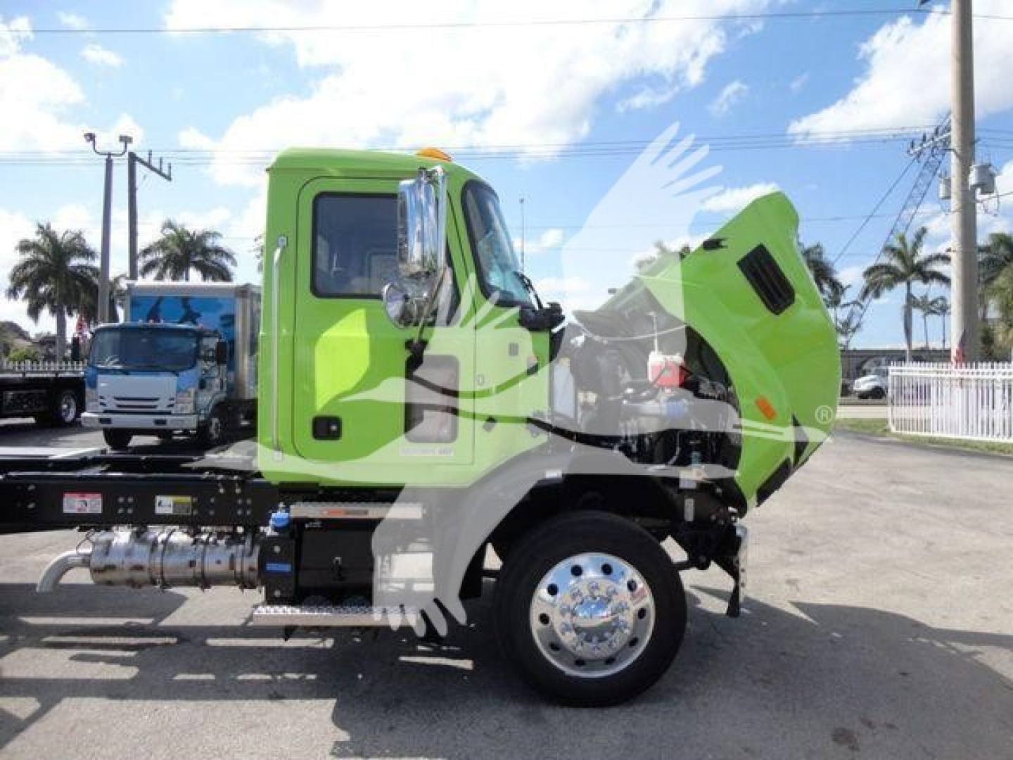 Green Mack MD6 rollback truck with hood open, side view showing cab and chrome bumper, front wheel and exhaust piping.