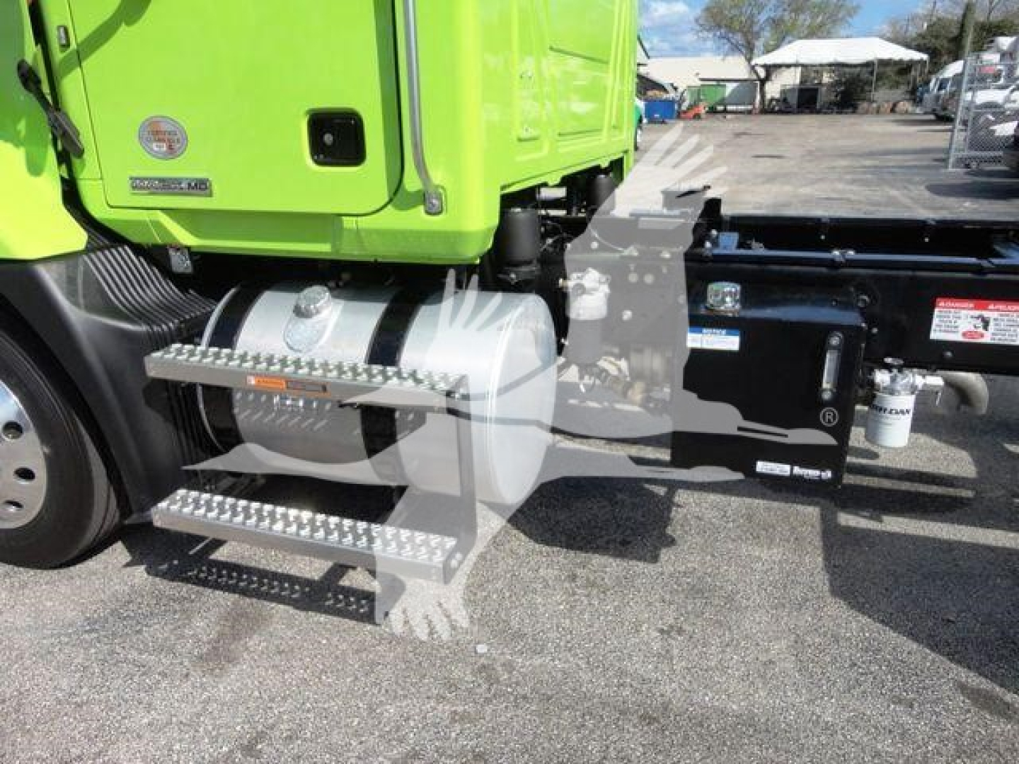 MD6 Mack truck side view showing green cab, chrome side steps, fuel tank, and chassis with hoses and equipment.