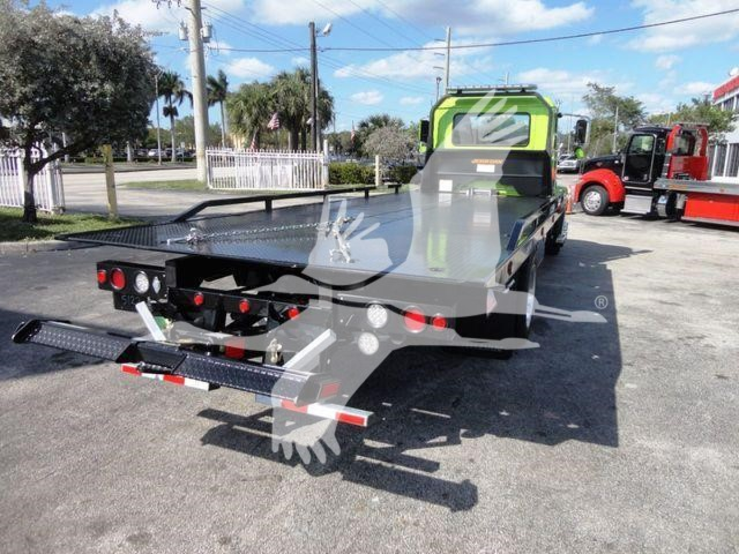 MD6 rollback truck bed showing green cab and hydraulic ramps with rear loading platform and warning lights.