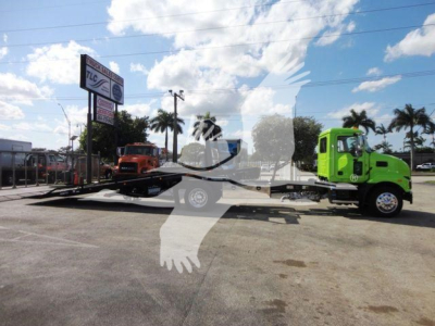 2026 Mack MD6 rollback truck on a trailer being displayed in a dealership lot with palm trees and blue sky in background.