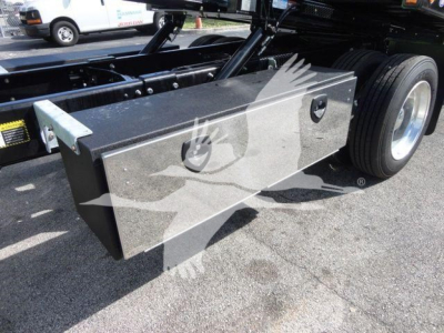 Truck chassis with large rectangular aluminum toolbox mounted near rear wheels, visible tire, undercarriage, and hydraulic lines. No legible serials or model numbers visible.