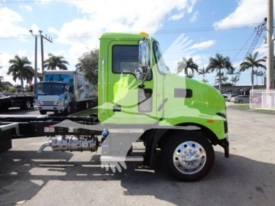 Green Mack MD6 truck cab in profile, side view showing front wheel, fuel tanks, and chassis; no visible equipment labels readable.