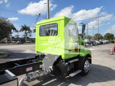 Green Mack MD6 rollback truck cab and chassis, side view showing cab with door, exhaust pipe, fuel tank, and step; no visible plate text.