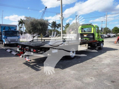 MD6 Mack rollback truck with a green cab and flatbed/carrier in a lot, showing a transporter bed and ramps.