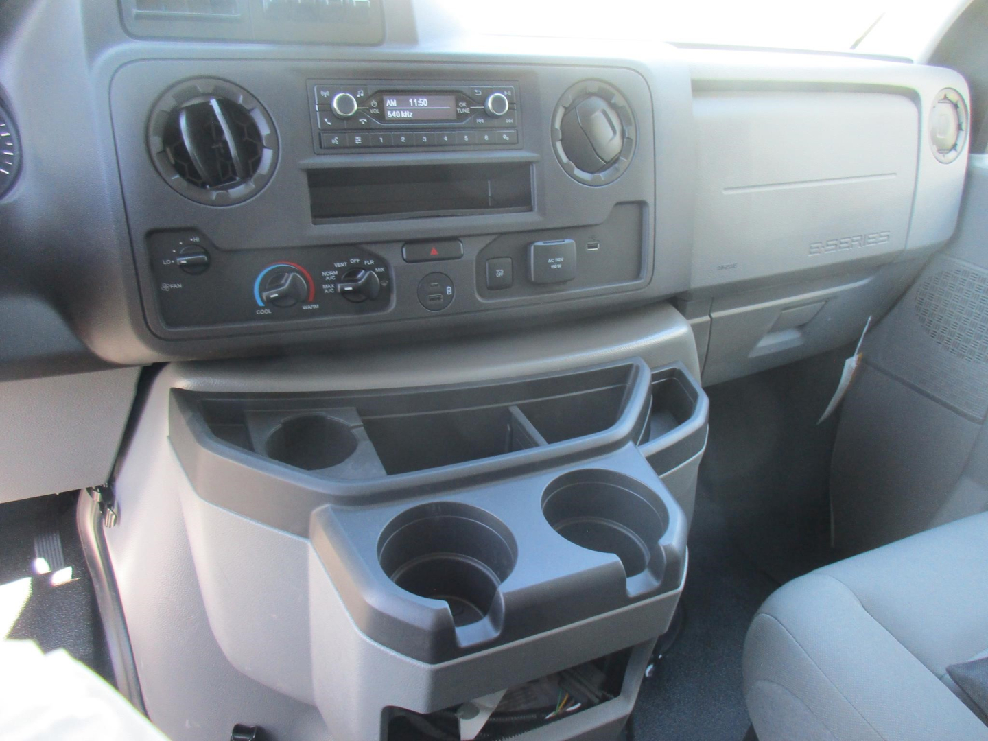Ford E-350 dashboard and center console showing cup holders and storage compartments in view.