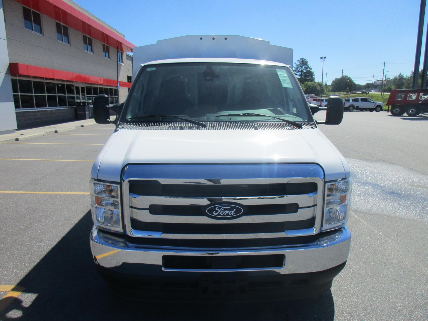 Ford E-350 cargo van front view showing chrome grille and Ford emblem, white body, headlights, and bumper.