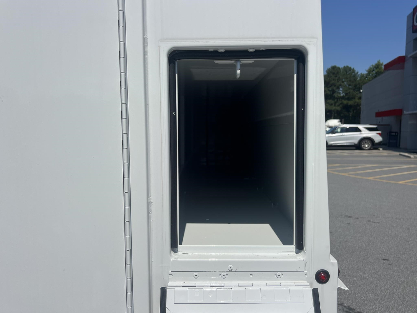 Ford E-Series van or service body rear cargo opening showing empty interior with door frame and small light at top; exterior white paint.