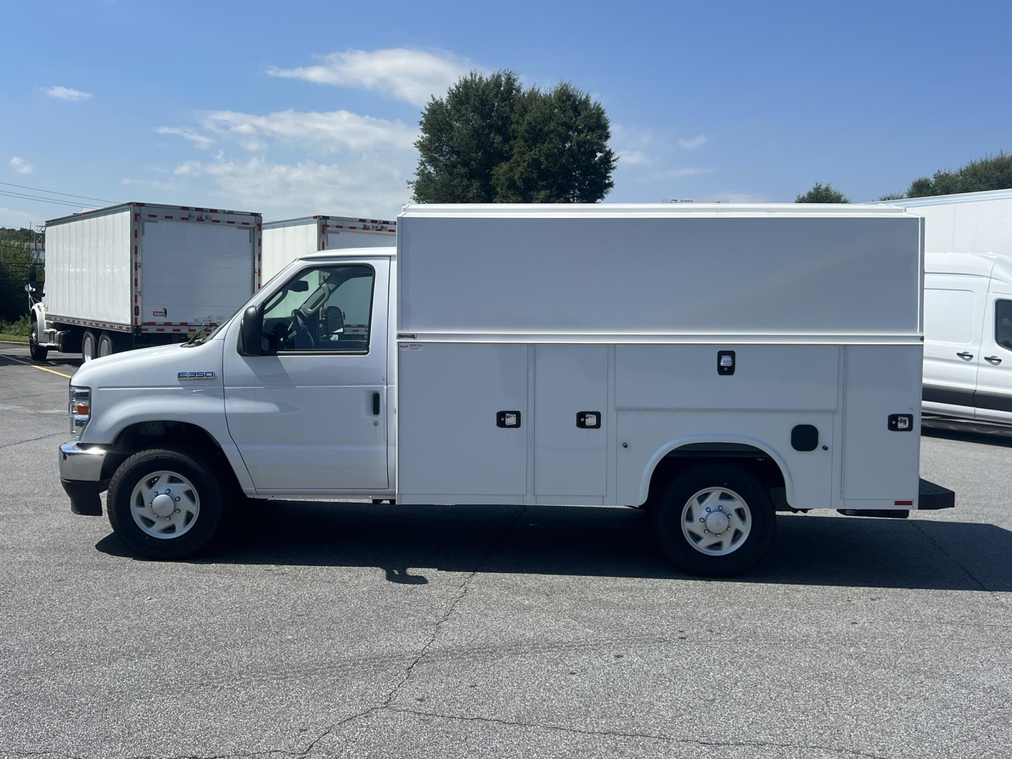 Ford E-350 service utility van side view with multiple storage compartments and toolbox doors visible.
