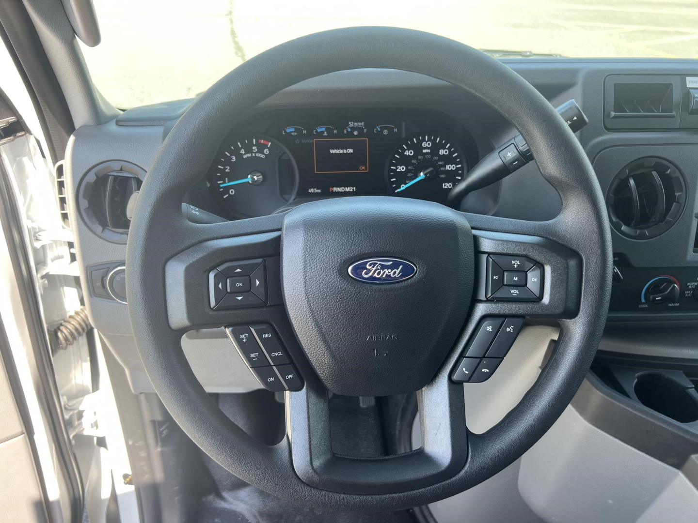 Ford steering wheel in a Ford E-350 interior showing left and right control stalks; instrument cluster visible in background.