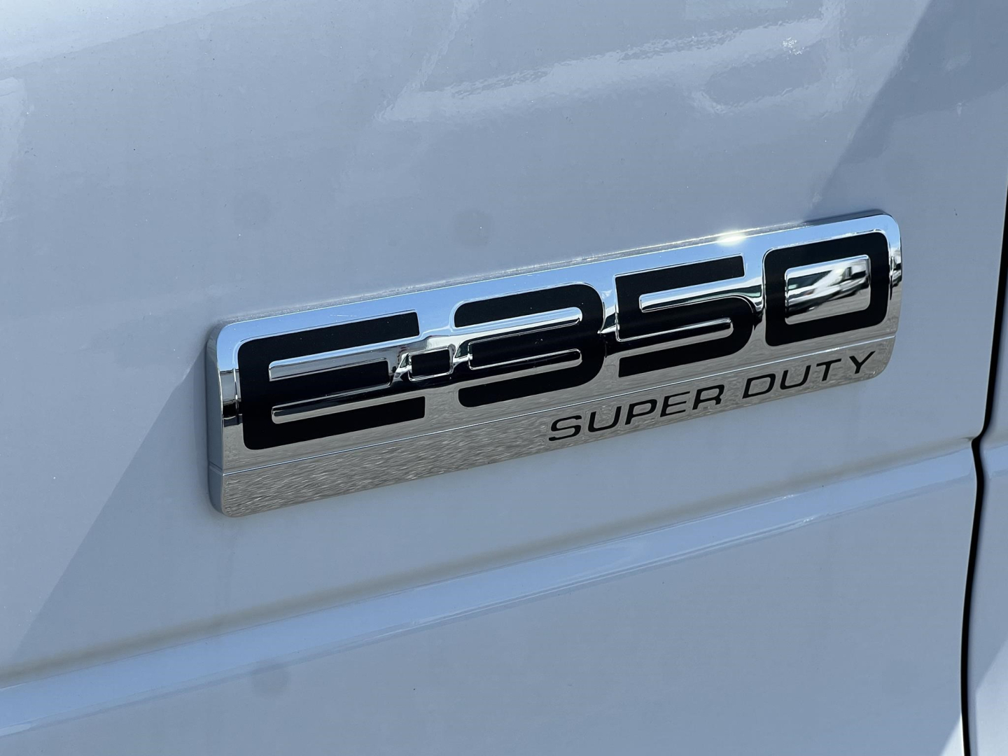 Ford E-350 Super Duty badge on the side of a white van showing 'E-350' and 'SUPER DUTY' text.