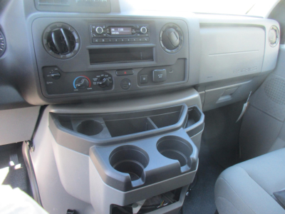 Ford E-350 dashboard and center console showing cup holders and storage compartments in view.