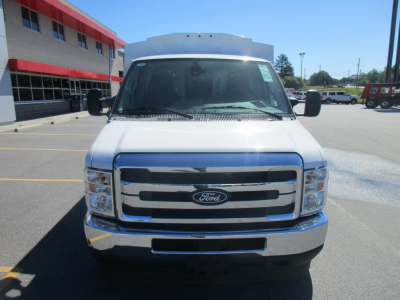 Ford E-350 cargo van front view showing chrome grille and Ford emblem, white body, headlights, and bumper.
