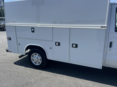 Ford E-350 service utility van rear-side compartment doors and wheel shown.