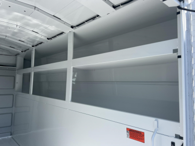 Van interior showing empty metal shelving on both sides in cargo area.