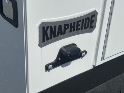 Back of a white service/utility truck/trailer with a KNAPHEIDE logo plate and black handle latch in foreground.