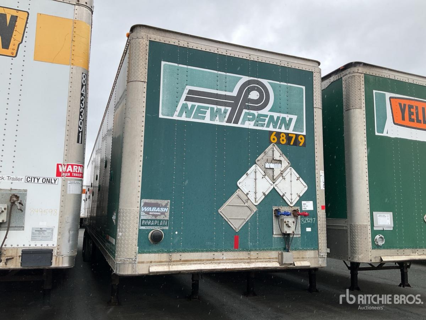 Trailer back view showing New Penn logo and safety decals on green Wabash trailer with platform and rear bumper.