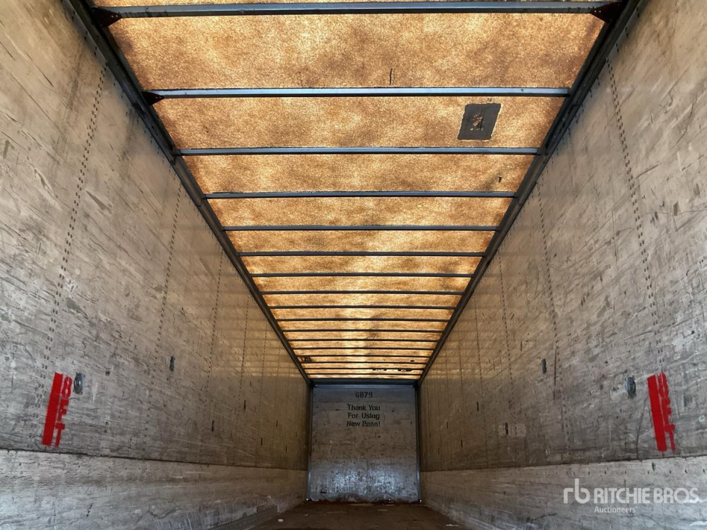 Trailer interior showing tall, empty cargo bay with wooden roof panels and metal side walls. Ritchie Bros branding and red safety handles on both walls.