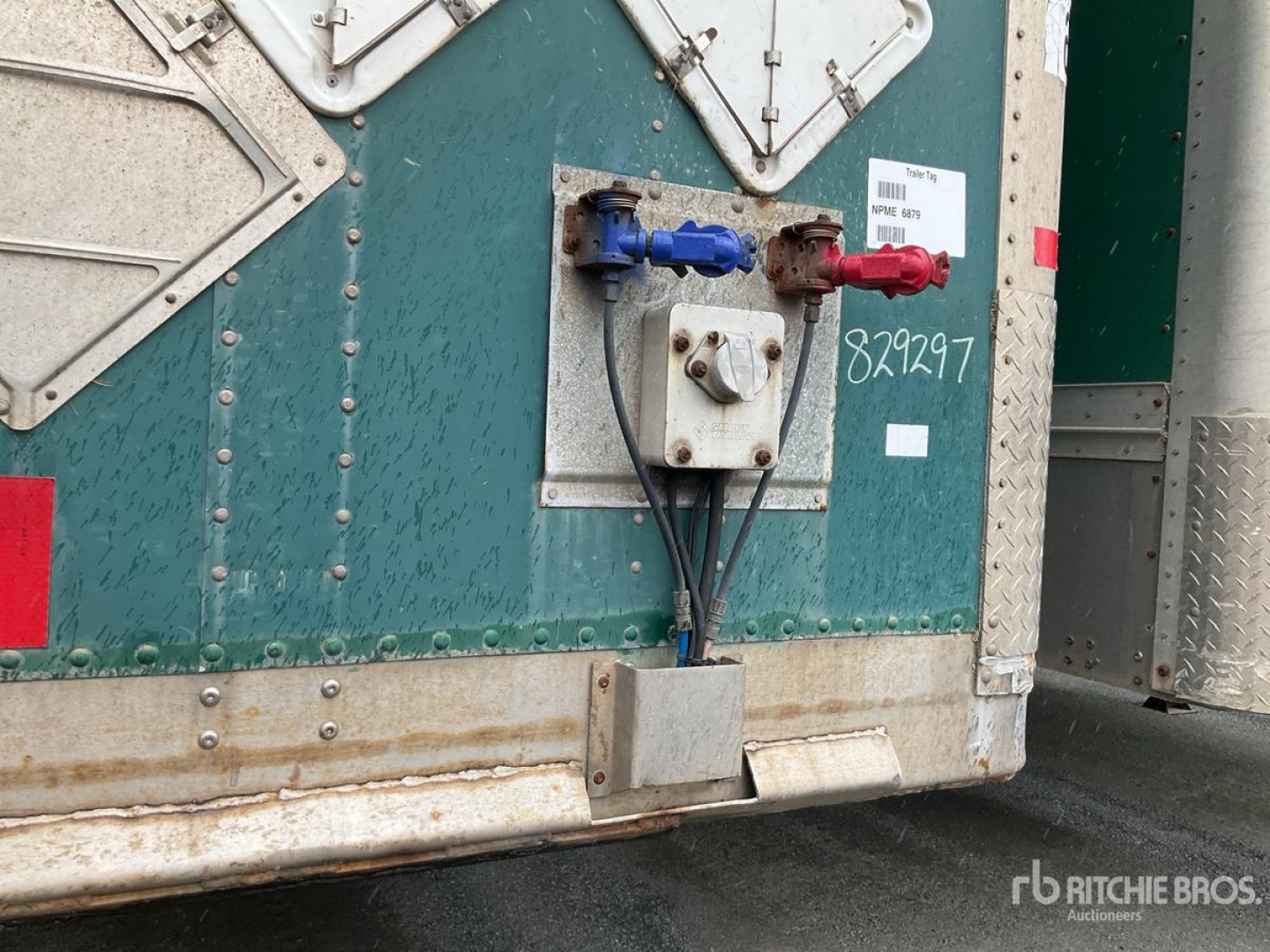 Trailer rear showing dual connections: blue and red air/electrical couplers and a central square control box mounted on a green Wabash trailer.