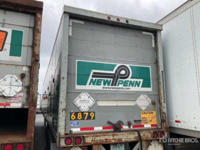 Rear view of a New Penn trailer with green logo, license plate-style numbers 6879, caution sticker, and reflective tape.