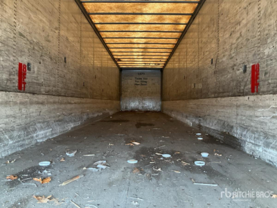 Trailer interior showing empty cargo area with dirt and debris, wood sidewalls, and overhead lighting.