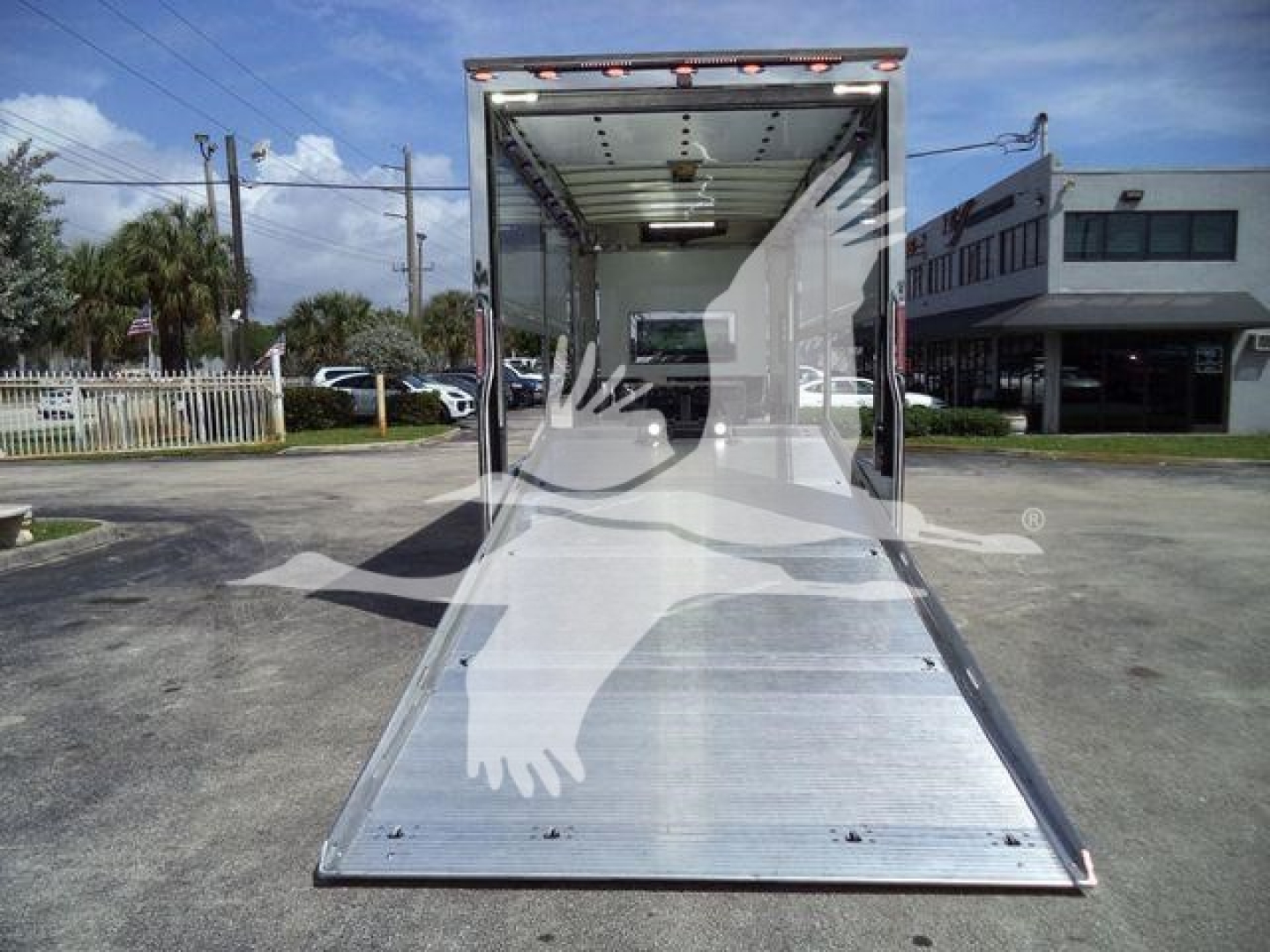 Open truck rollback with ramp down, interior shows empty cargo area, loading dock in background.