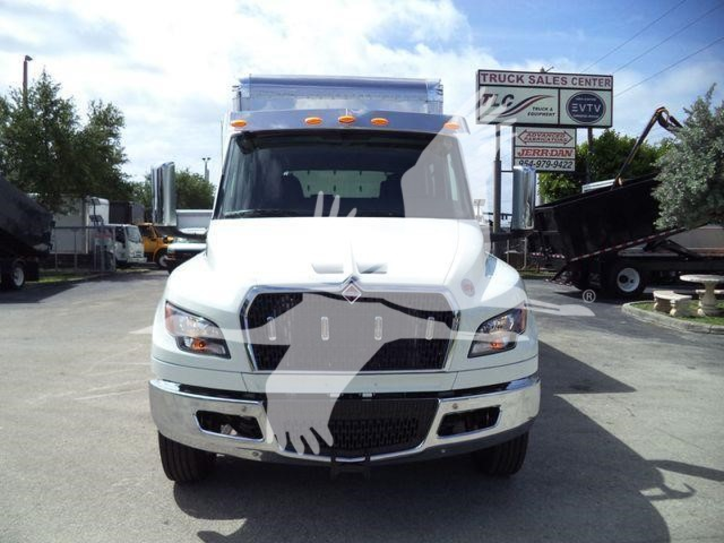 Truck front view showing International MV model cab, white exterior, grille, headlights, and bumper in a dealership lot.