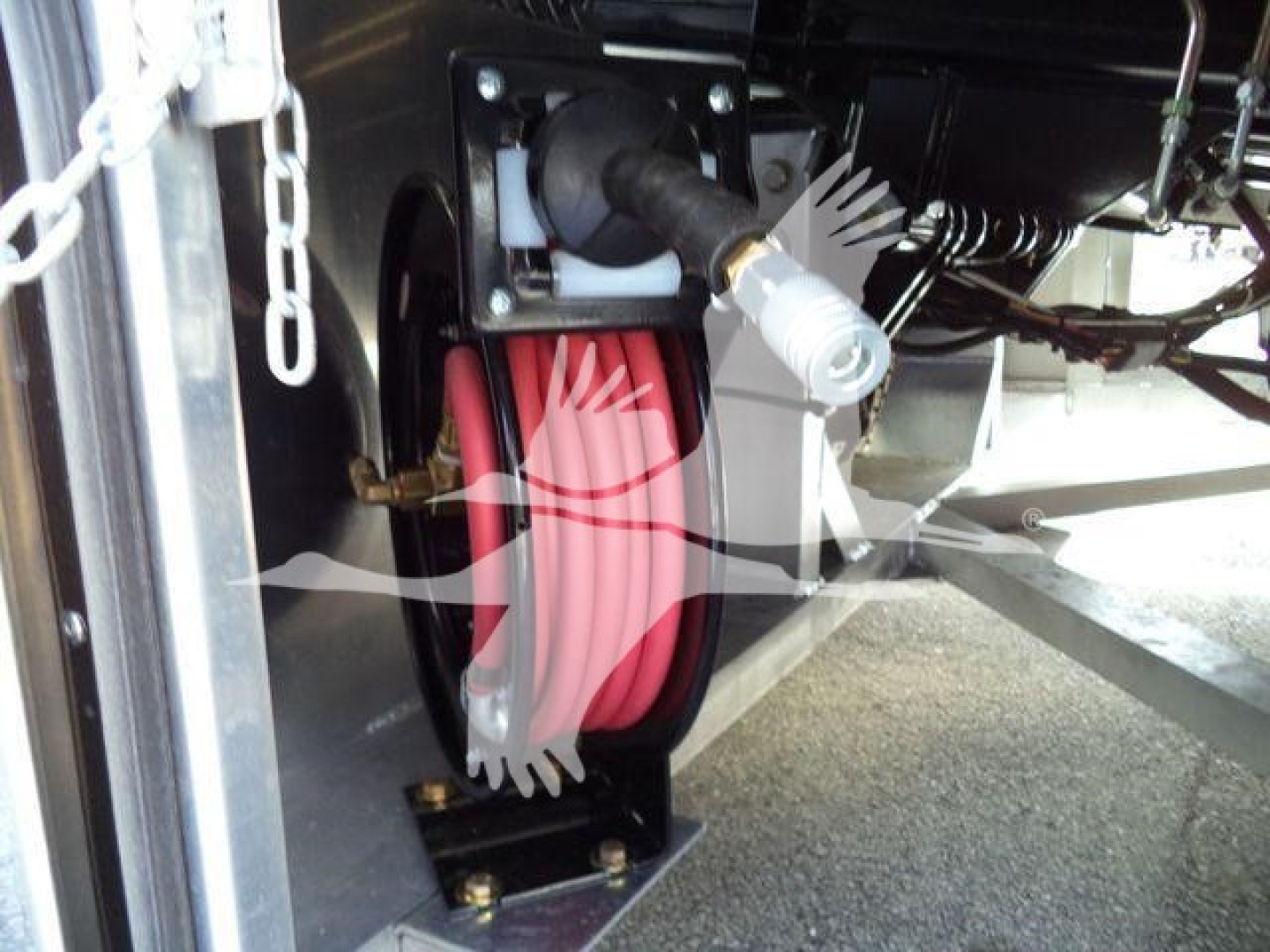 Trailer hydraulic hose reel with red hose and metal mounting bracket in a stock International MV rollback truck setup.