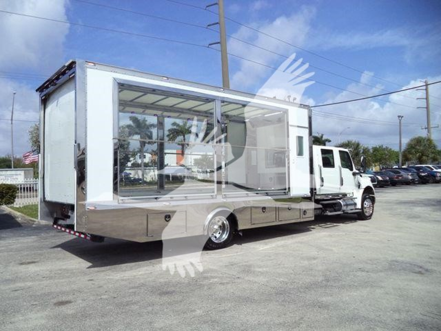 Truck-mounted mobile showroom/box truck with large glass display windows on side, International MV chassis, white and chrome accents, parked in a lot.