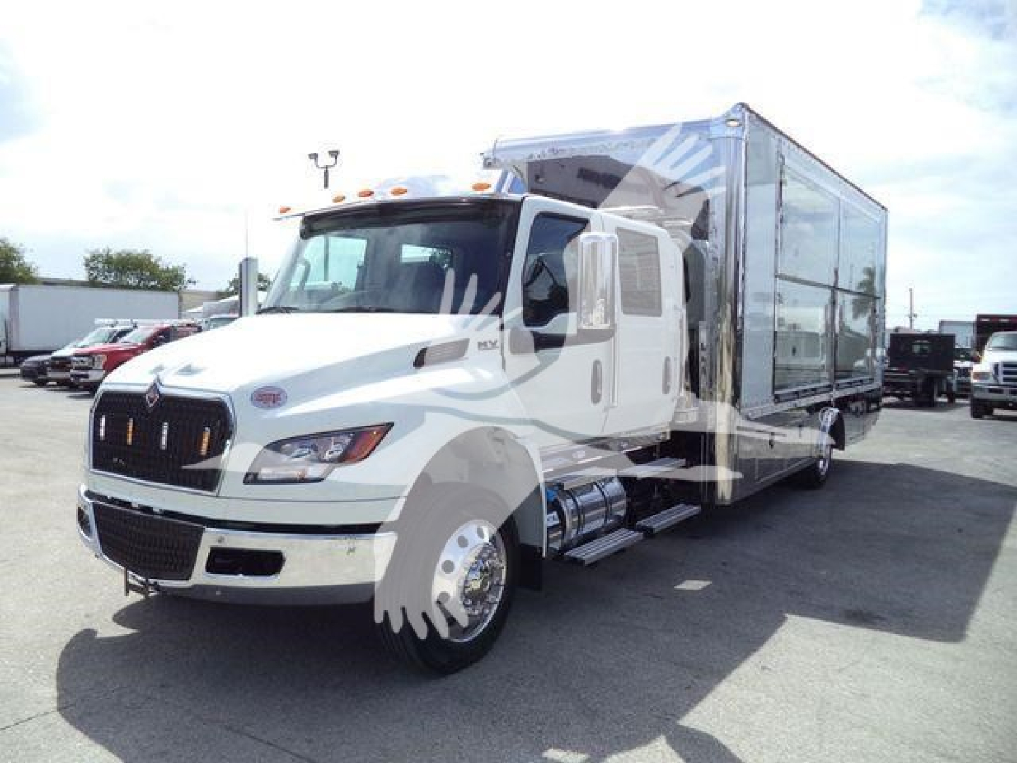 International MV rollback truck with a large box trailer in a dealership lot.