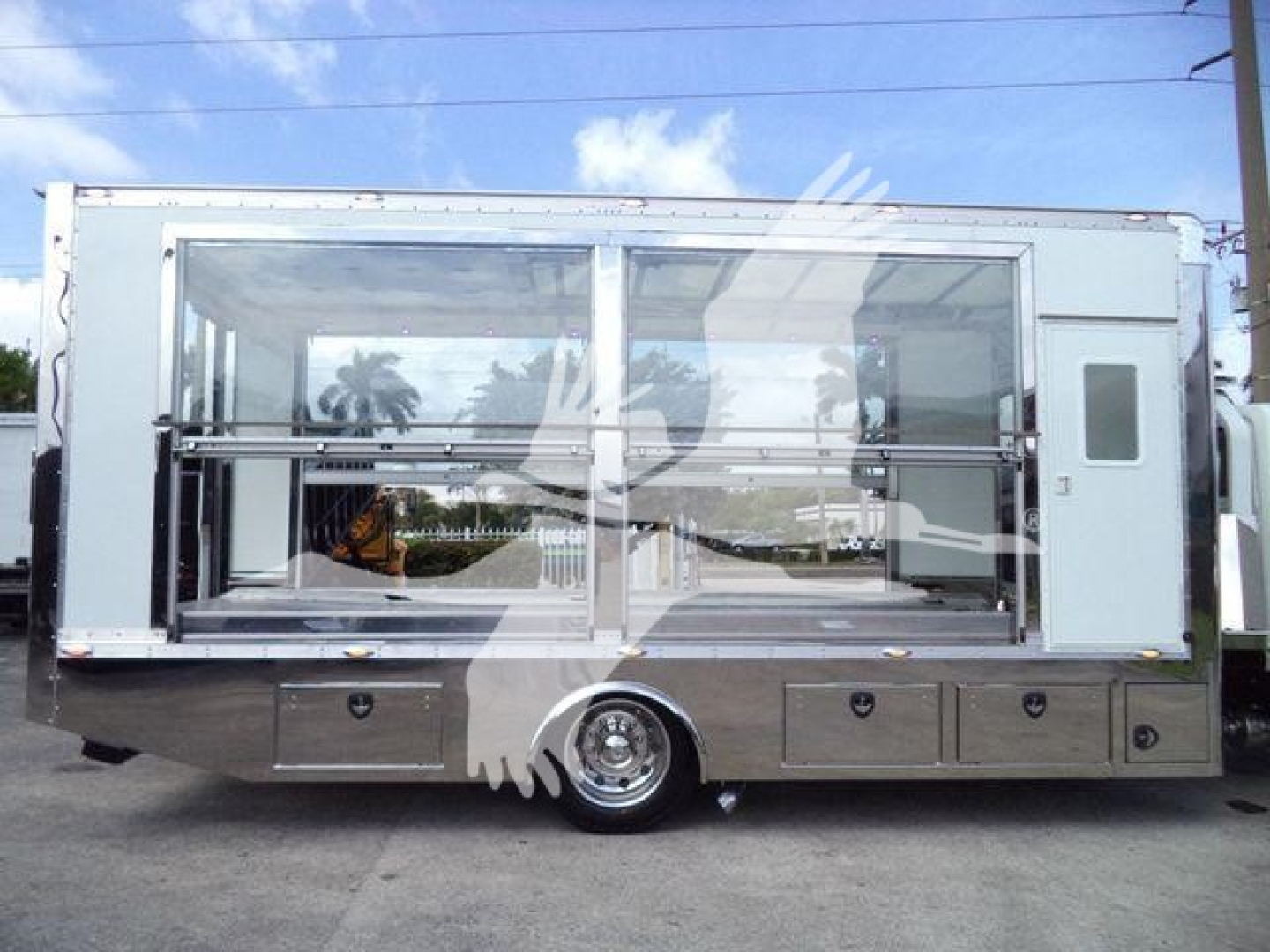 Truck body side view showing large glass display with metal frame, storage drawers under, and wheel in center; International MV rollback unit.