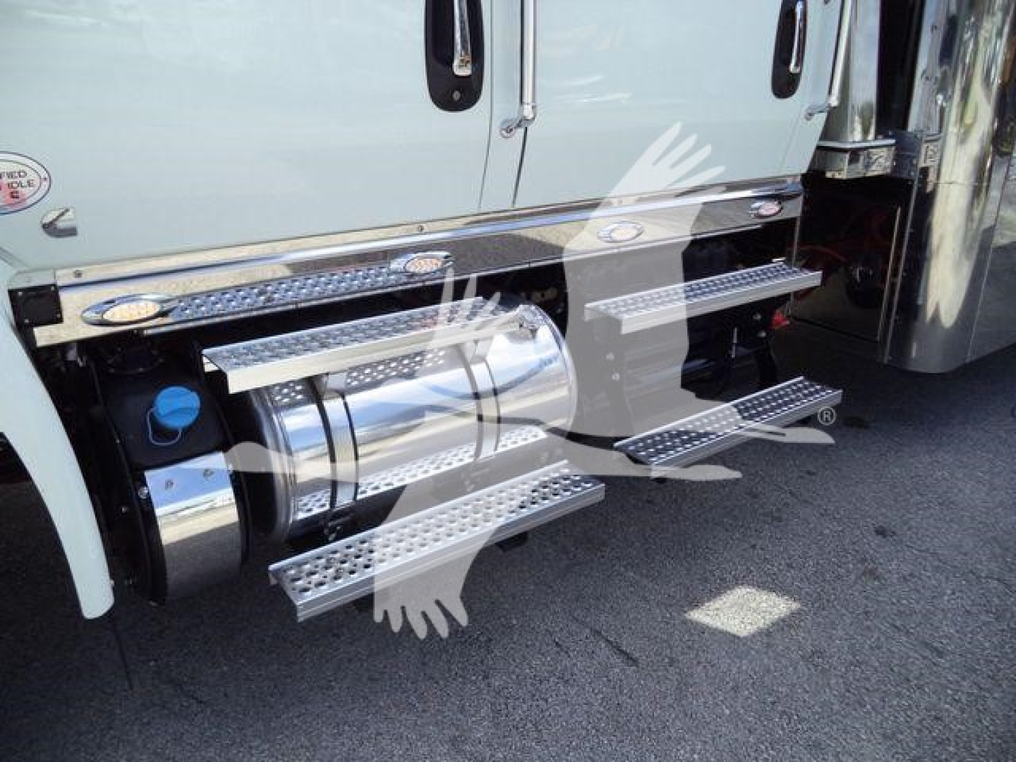 Trucks side view showing chrome cylindrical fuel tank and aluminum step rails along the cab of a 2027 International MV rollback truck.