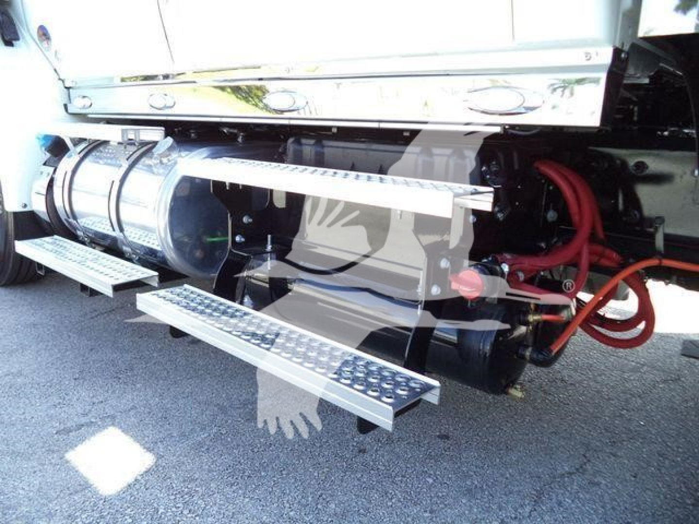 Truck side showing chrome fuel tanks and red hoses with steps extending from the chassis.