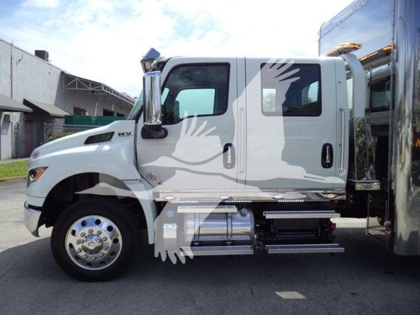 MV Series International rollback truck side view showing cab and chrome fuel tanks and steps with logo and text on door.