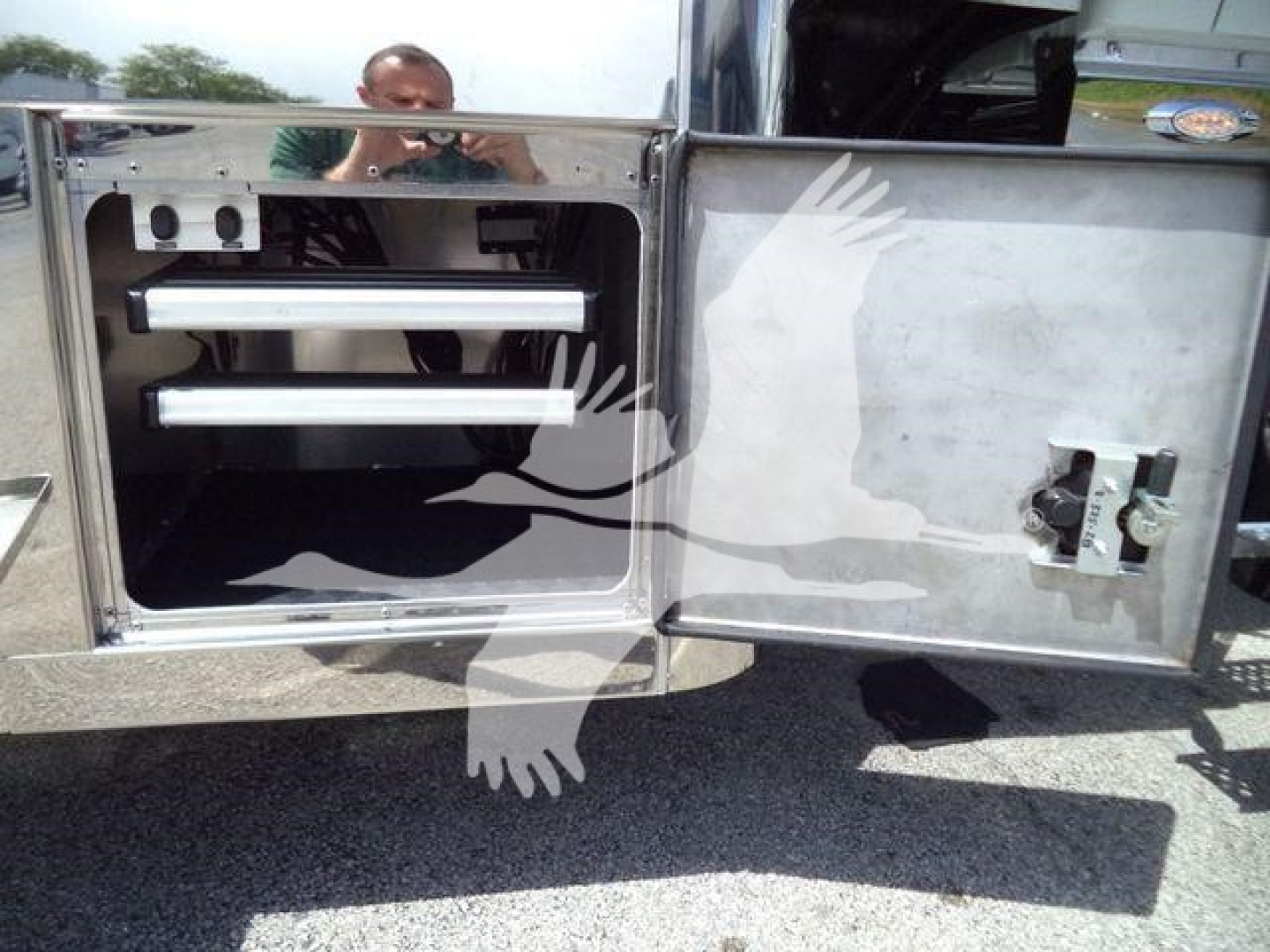 International MV rollback truck storage compartment with chrome shelves and metal door.
