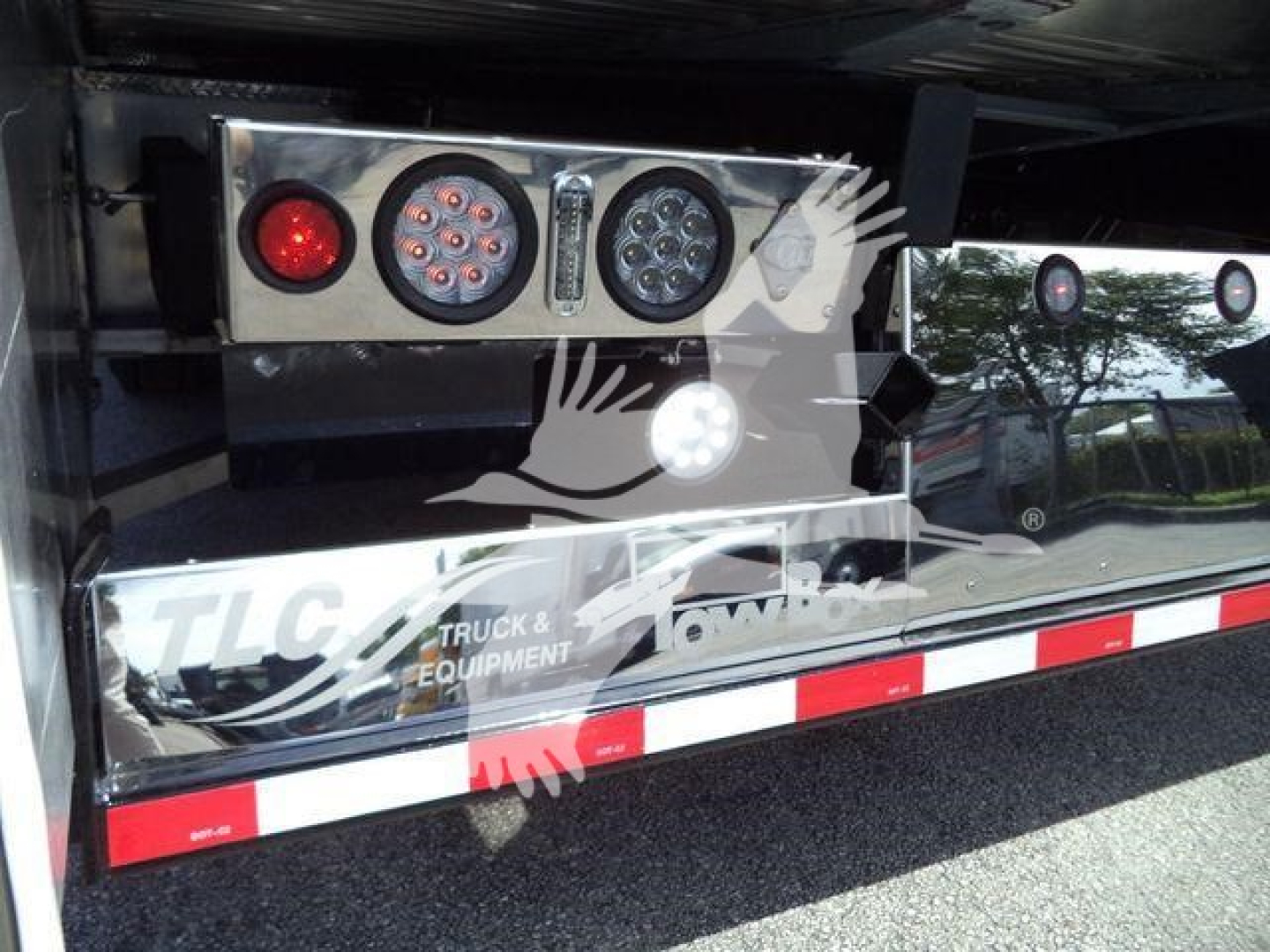 Back of a rollback truck showing round taillights and LED lights, with TLG Truck & Equipment branding on rear undercarriage.