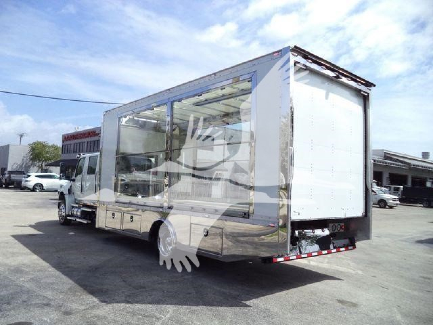 Truck-mounted rollback / car carrier style body on a white International MV chassis with clear side windows and a rear loading ramp.