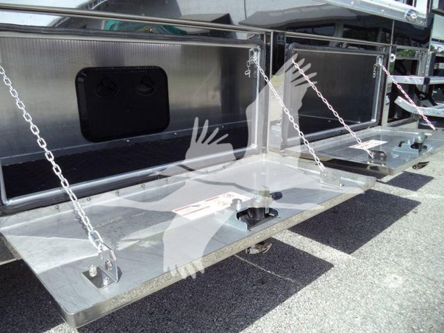 Truck rollover bed with metal steps and chains, storage compartments, and instructional labels visible on a flatbed trailer