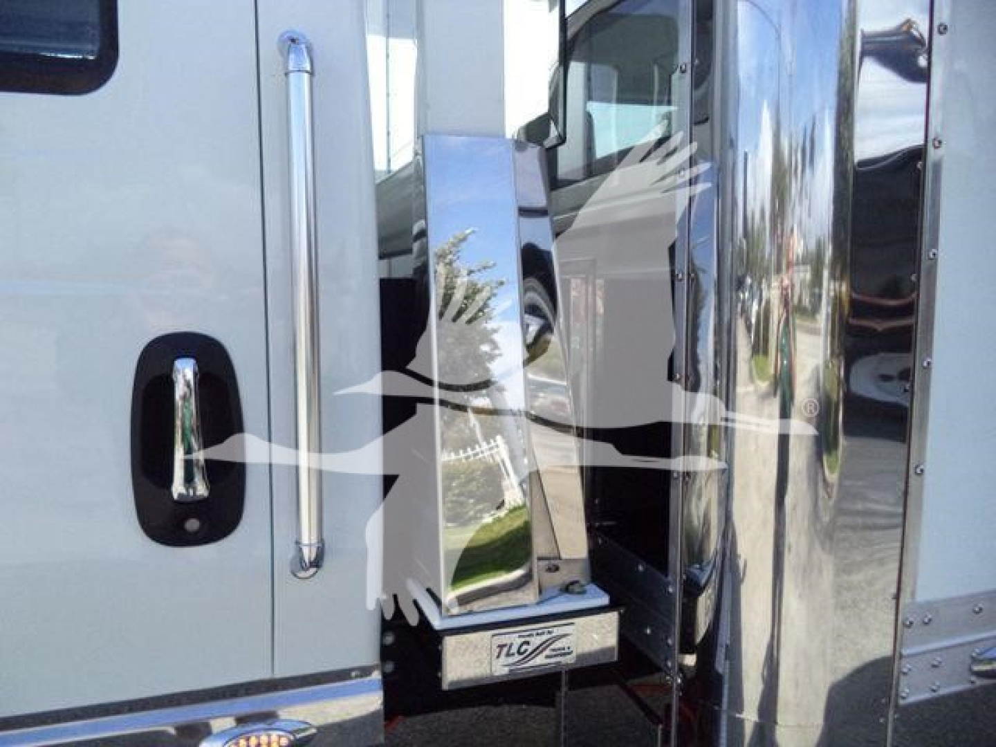 Truck cab side and chrome steps on a new 2027 International MV rollback truck showing polished exterior and access step with TLC logo.