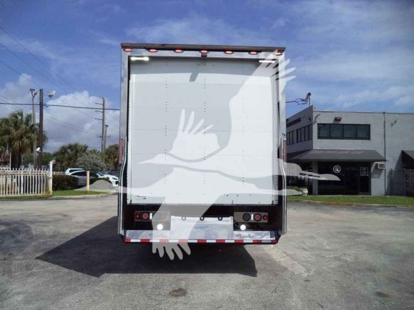 Rear view of a blank cargo box on a rollback truck with taillights and reflective bumper.