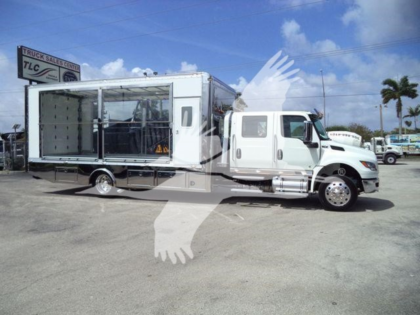 Truck for sale: 2027 International MV rollback unit with a large box body and crane mount, white cab, right-side step and chrome fuel tanks.