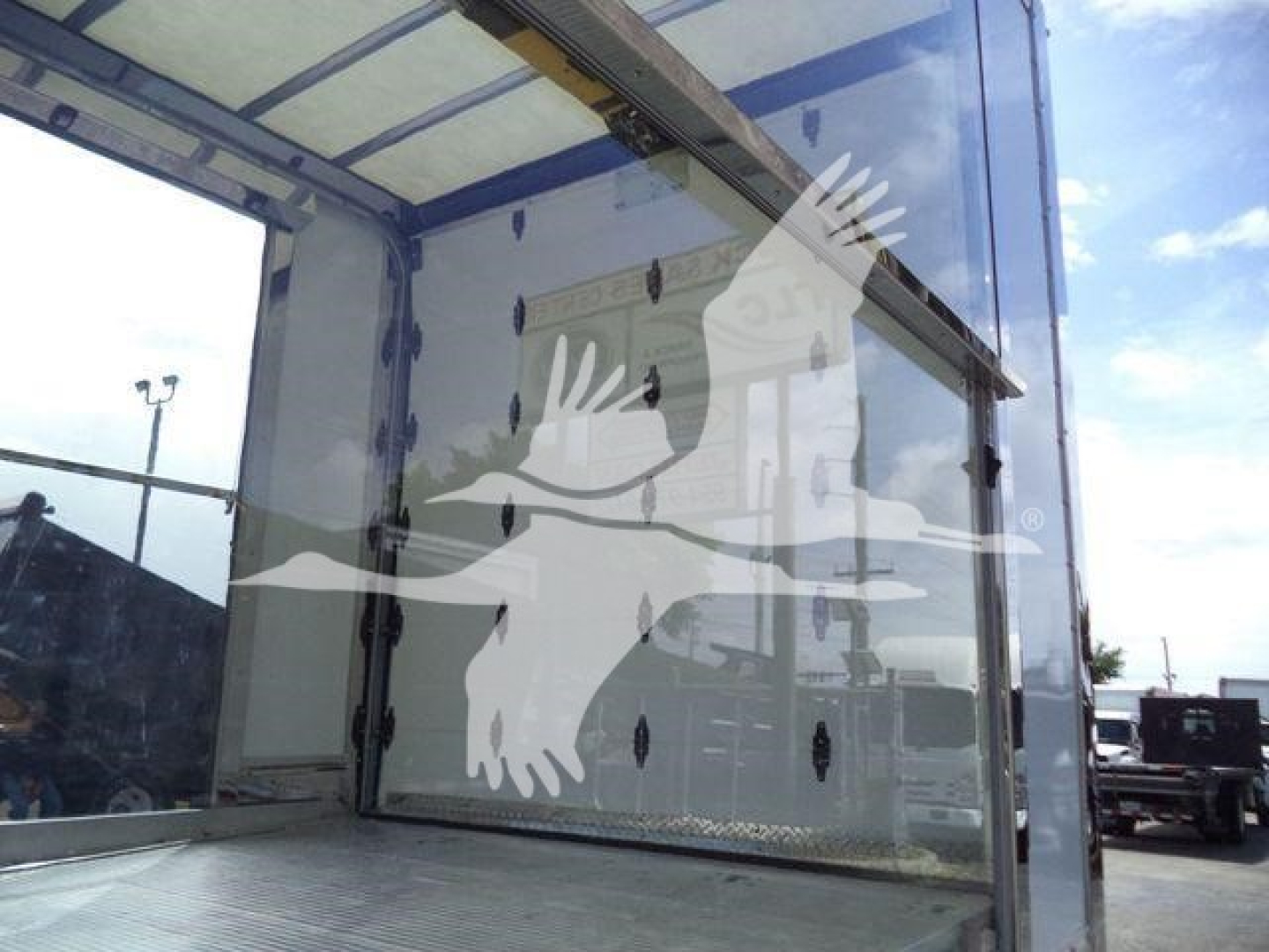 Trucks showing cargo area with roll-back bed and aluminum interior; rear overhead door opening; stock number TOWBOX8CLEAR visible.