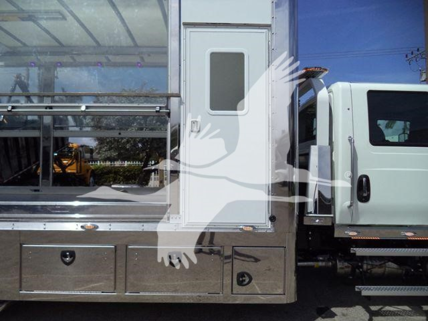 Truck cab and service body of a 2027 International MV rollback truck showing storage drawers and side door.