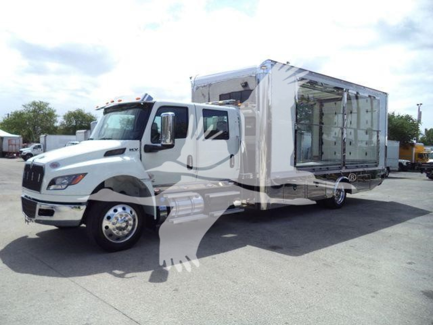 Truck in a rollback configuration with a large white cab and open side panel showing interior storage area.