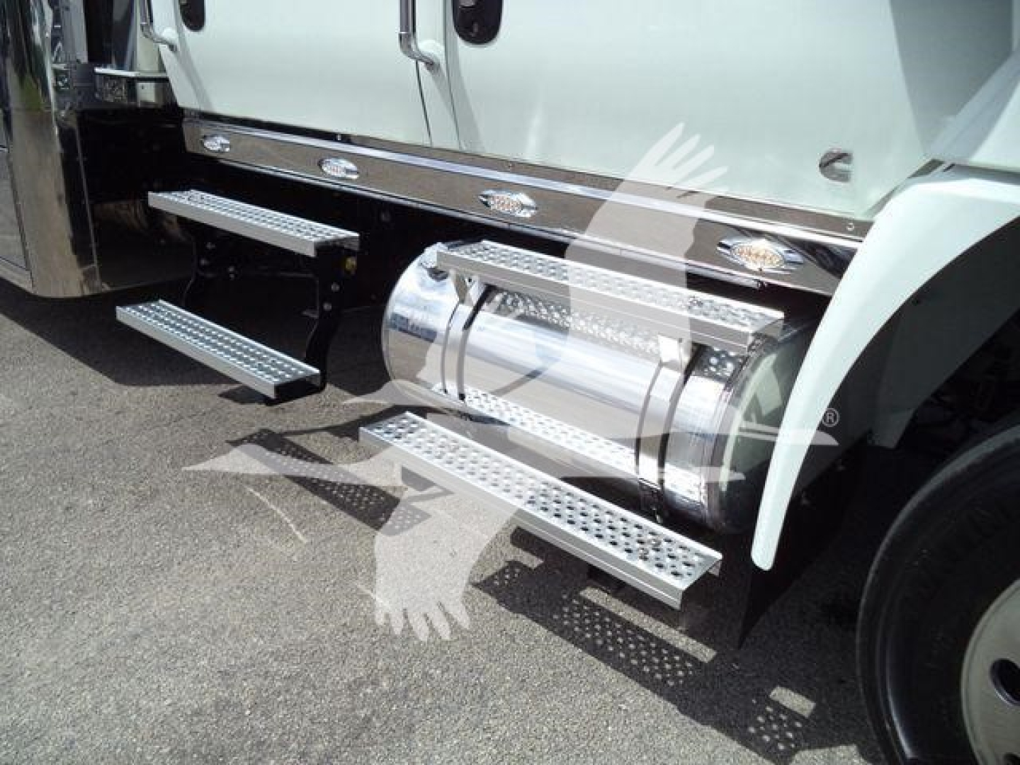 Truck side steps and fuel tanks on a white International MV truck showing chrome "+" running boards and dual tanks.