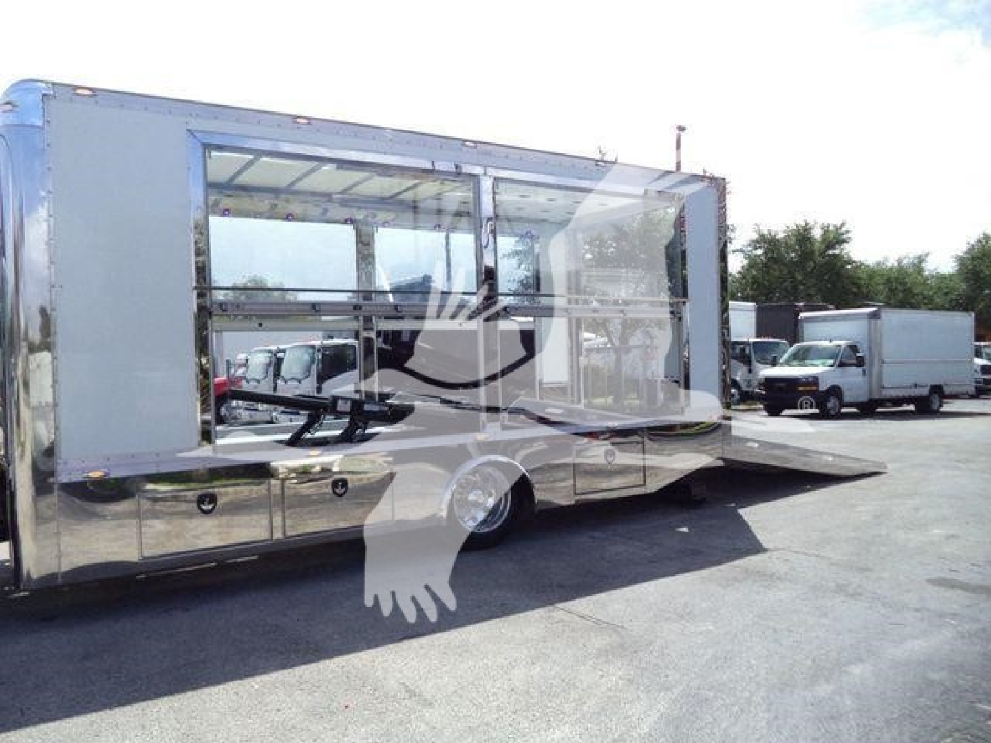 Large white crew cab rollback truck with side awning and interior seating visible through windows.