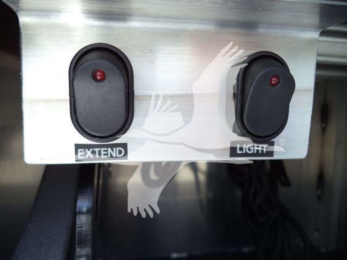 Controller panel with two black rocker switches labeled EXTEND and LIGHT, red indicator LEDs, mounted on a metallic surface.